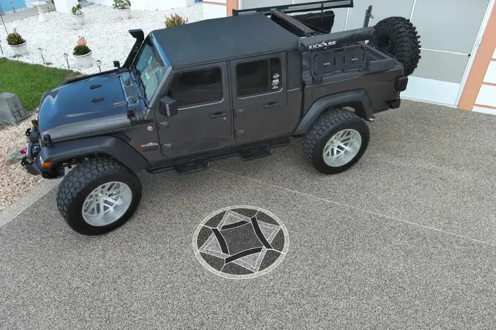 Gray resin bound driveway with a compass-star inlay beside a parked truck