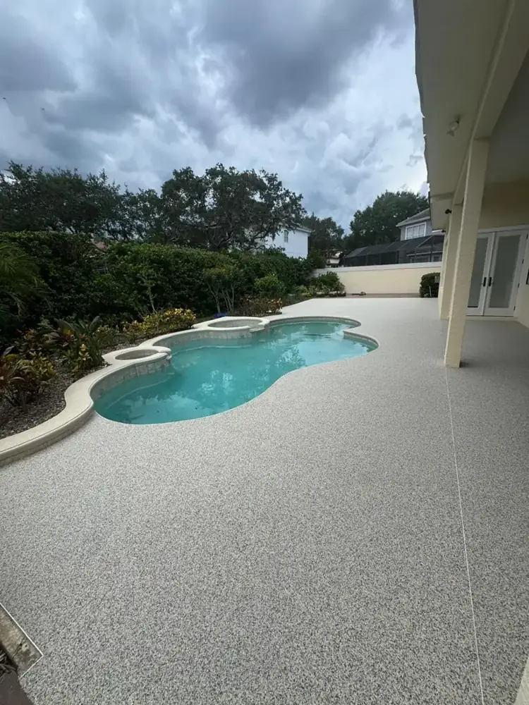 Light gray resin bound pool deck around a freeform pool